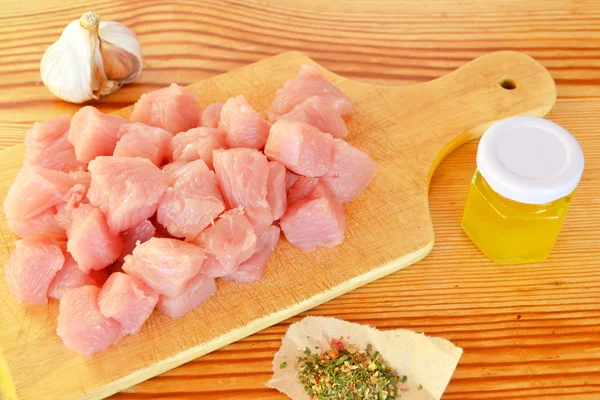 Tumpukan potongan daging sapi mentah di papan potong kayu, bawang putih, rempah-rempah, minyak zaitun. Potongan daging. Daging dipotong menjadi batu . — Stok Foto