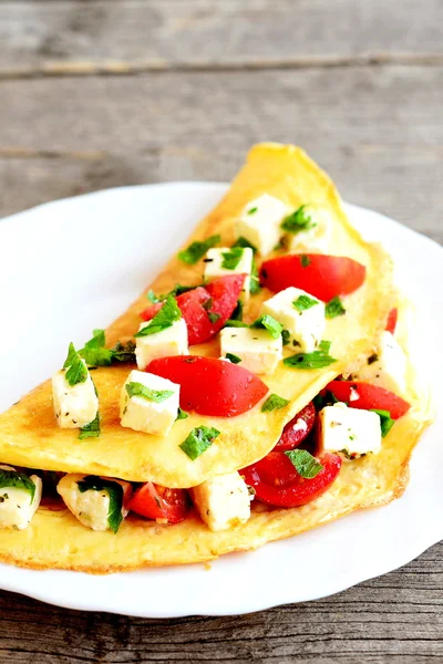 Omelett mit Käse, Tomaten und Petersilie auf einem Teller auf altem Holzboden. gefülltes Omelett Rezept. Nahaufnahme — Stockfoto