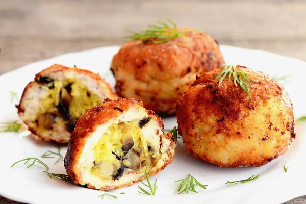 Bolas de carne fritas recheadas com queijo ralado e cogumelos fritos. Os rissóis de carne enchidos em uma chapa e no contexto de madeira. Receita de cozinha caseira. Fechar. — Fotografia de Stock