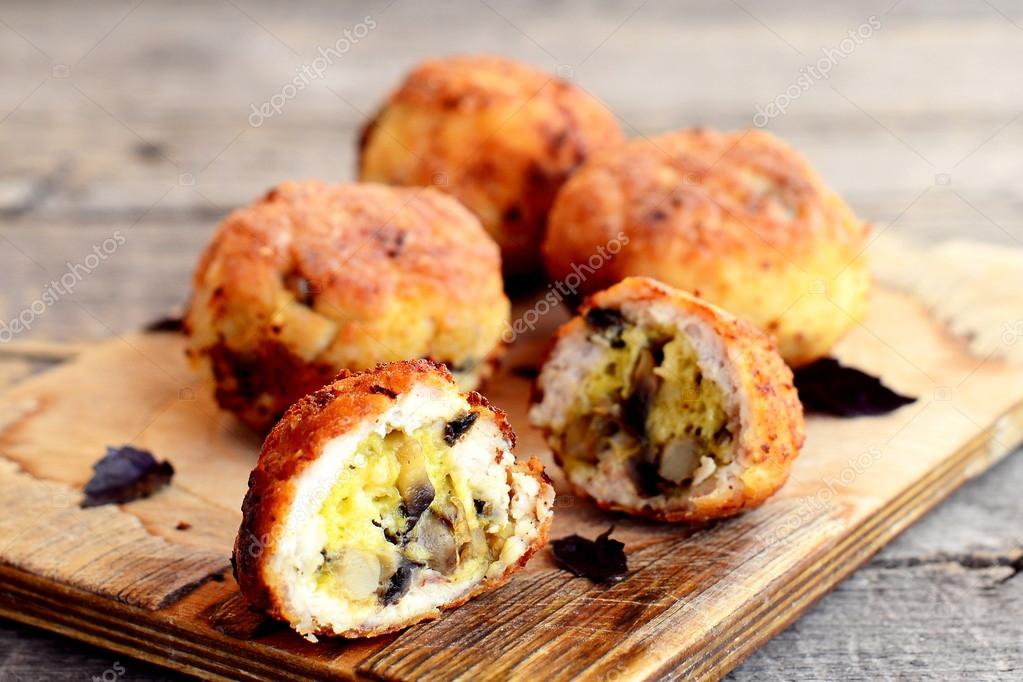 Fried meat patties filled with cheese and fried mushrooms on board and