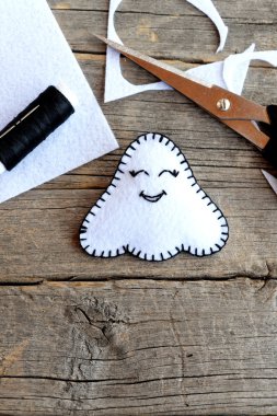 Sevimli Cadılar Bayramı hayalet süsü, makas, siyah iplik, eski ahşap arka planda keçe parçaları ve kırıntıları. Hayalet süsü dikmek için el işi seti. Çocuklar için Cadılar Bayramı sanat fikri. - Yakın çekim. Dikiş dersleri adım adım öğreniliyor