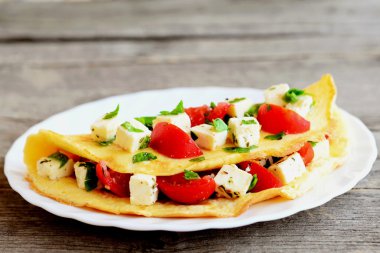 Eski ahşap arka plan üzerinde izole bir plaka üzerinde lezzetli dolma omlet. Kızartılmış omlet peynir, domates ve maydanoz ile doldurulmuş. Yumurta tarifi. Portre 