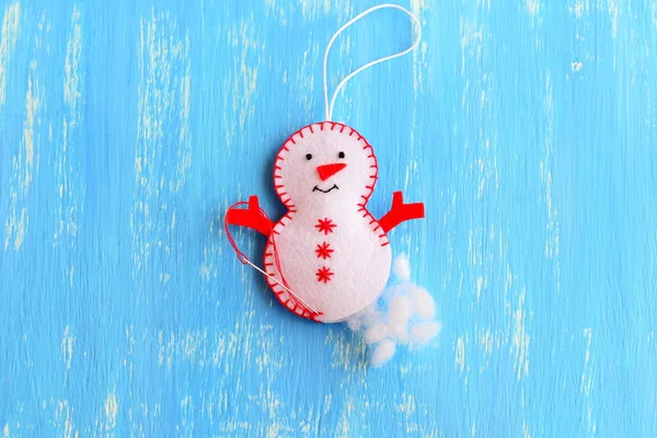 How to make a Christmas felt snowman ornament. Decortion step by step. Stuff the felt Christmas snowman ornament with hollowfiber. Kids Christmas tree ornament decoration sewing crafts. Blue wooden background. Top view — Stock Photo, Image