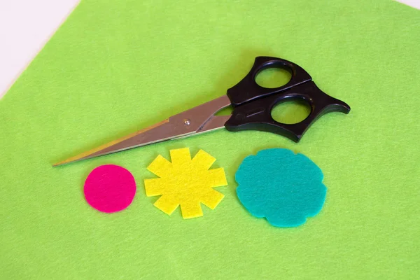 Cut felt yellow and turquoise flowers, pink circle. Scissors on a green background. Sewing set pattern. How to make handmade bright summer brooch. Step — Stock Photo, Image