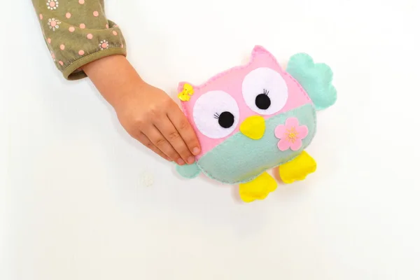 Child holds a felt owl toy in his hand. Child plays with a soft bird toy. Cute felt owl toy — Stock Photo, Image