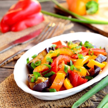 Haşlanmış biber patlıcan ve sarımsak. Kırmızı ve turuncu biber patlıcan ve sarımsak ile güveç ve doğranmış yeşil soğan ile tepesinde. Parlak sebze güveç tarifi. Portre 