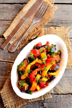 Kızarmış sebzeler bir plaka üzerinde ve eski ahşap zemin üzerinde. Kızarmış biber patlıcan, sarımsak ve yeşil soğan ile. İçten diyet yiyecek. Üstten Görünüm 