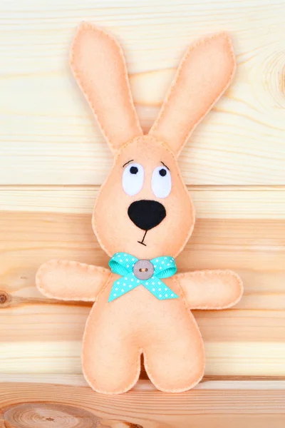 Beige Easter felt rabbit on a natural wooden board. Easter felt toy — Stock Photo, Image