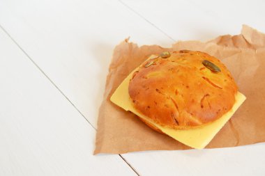 Bir dilim peynir kağıt ve beyaz tahta arka plan ile sandviç 