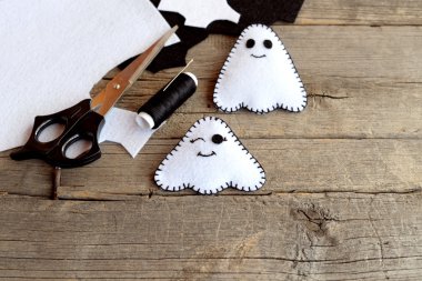 El yapımı Halloween hayaletler süsler. İki küçük hayalet, hissettim konu, eski ahşap arka plan üzerinde iğne artıkları, makas, hissettim. Şirin Halloween karakterler. Üstten Görünüm