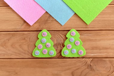 Noel süsü dikmeyi. Adım at. Ahşap bir arka planda pembe ve mavi halkalar ile süslenmiş yeşil bir Noel ağacı hissettim. Noel ağacı nakış işi. Üst Manzara. - Yakın çekim. Çocuklar için Noel ağacı dikme sanatı.