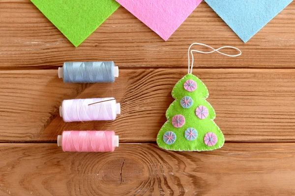 How to sew Christmas decoration. Step. Green felt Christmas tree embellishment, thread, needle on a wooden table. Hanging ornament Christmas tree. Top view. Felt Christmas tree decoration sewing crafts for kids guide — Stock Photo, Image