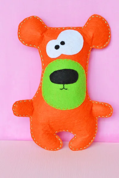 분홍색 배경에 오렌지 펠트 장난감 곰 — 스톡 사진