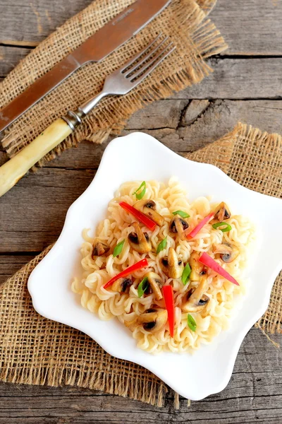 La pasta de setas con hortalizas en el plato. Pastas caseras con champiñones asados, pimiento rojo y cebolla verde. Plato vegetariano. Vista superior — Foto de Stock