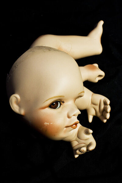 Close Up of Broken Doll Heads and Parts On Black Background