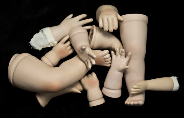 Close Up of Broken Doll Heads and Parts On Black Background