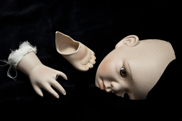 Close Up of Broken Doll Heads and Parts On Black Background