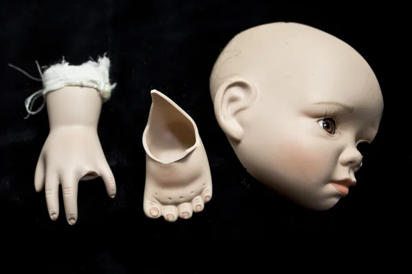 Zbliżenie na złamaną lalkę głowy i części na czarnym tle — Zdjęcie stockowe