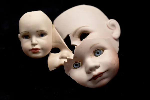 Gros plan des têtes et des pièces de poupée cassées sur fond noir — Photo