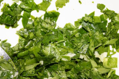 Beyaz arka planda doğranmış kişniş ve maydanoz otlarını kapatın.