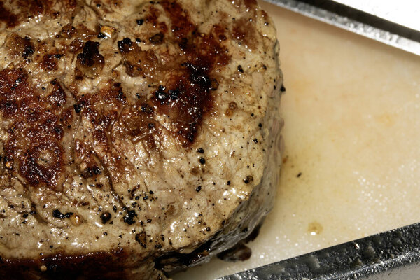 Close up of seasoned cooked steak resting on a white chopping board