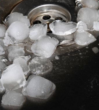 Eriyen buz küpleri lavabo kapağından damlıyor gümüş metal leğen boşaltılıyor.