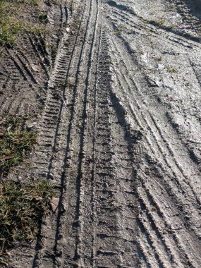 Yolun derin çamurlu tarafında araba lastiği izleri var.