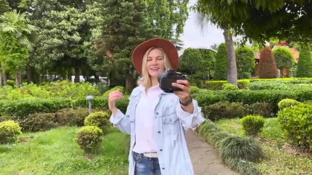 Blogueiro filmando a si mesma na câmera no jardim — Vídeo de Stock