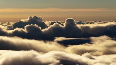 Kabarık bulutlar denizinin üzerinde büyüleyici bir manzara. Güneş ufukta altın bir parıltı ve Pico do Arieiro Madeira yakınlarında bulutlar oluşturarak batıyor..