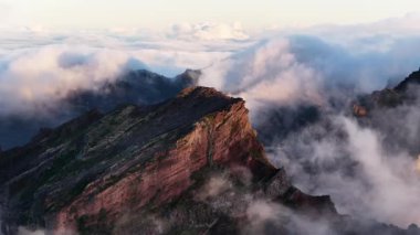 Majestic Kayalık Dağı, Madeira 'nın merkezindeki bulutları delip geçer. Sabahın erken saatlerinde manzara aydınlanır. Sis tepelerin etrafında sürükleniyor.