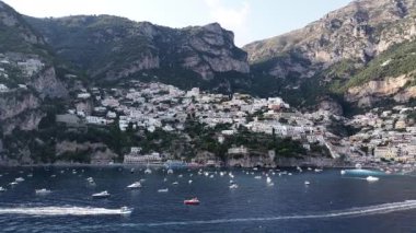 Positano İtalya 'nın kıyı kenti yakınlarındaki sularda gemiler yüzüyor. Arka planda dağlar yükselir. Yaz boyunca güneşli bir gün..