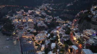Hava perspektifi, alacakaranlıkta Positano İtalya 'nın uçurum kenarındaki köyünde aydınlatılmış binalar ve caddeleri gösteriyor. Amalfi kıyısındaki sönen ışıkta ışıklar parlıyor..