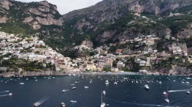 Tepedeki manzara güzel Positano kasabasını gösteriyor. Dağ boyunda renkli binalar. Çeşitli tekneler Tyrhenian Denizi 'ni geçiyor. Popüler bir seyahat noktası.