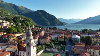 Sakin göl köyüne bakan ortaçağ çan kulesi, saat yüzlü ve çan kulesi gökyüzüne hakim, kaldırım taşına.