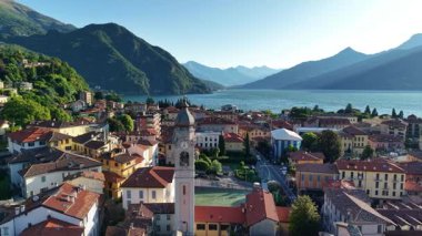 Göller körfezi üzerindeki canlı öğlen havası, berrak mavi su ve güneşli çatılar, yoğun marina noktaları, yemyeşil tepeler.