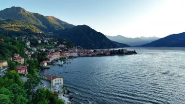 Panoramik kıyı şeridi ve deniz kenti yumuşak dalgalar, yeşil uçurumlar, demirlemiş tekneler ve yumuşak akşam ışığı