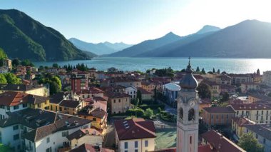 Kıyı kilisesi ve göl kıyısında aydınlık bir sabah, tepenin ardında yükselen güneş, çatılardaki sıcak ışık.,
