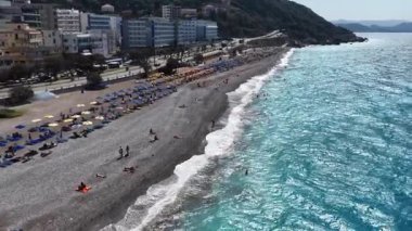 Rodos Yunanistan 'daki Ixia Sahili' nin üzerinden uç. Parlak turkuaz su çakıl taşı plaj otellerini ve güneşli günün tadını çıkaranları görün. Güzel bir yaz kıyısı.