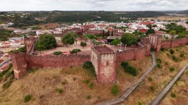 Yüksek bir manzara Portekiz 'in Algarve bölgesindeki tarihi Silves Kalesi' ni gösteriyor. Kale duvarları ve çevresindeki manzaralar gösteriliyor. Güneşli bir gün..