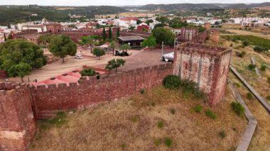 Algarve Portekiz 'deki Silves Kalesi havadan izleniyor. Antik kırmızı tuğla kuleleri ve kasabanın ve kırsal kesimin manzarasını keşfedin..