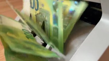 Bir para sayma makinesi 100 Euro 'luk banknotları hızla işlerken gösteriliyor. Makine gün boyunca hızla büyük bir para yığını sayar.
