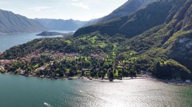 Bu, İtalya 'daki Como Gölü' nün manzaralı bir perspektifini gösteriyor. Mavi suyu çevreleyen yeşil ağaçlarla kaplı dağlar. Gündüz vakti gölde küçük bir tekne geziyor..