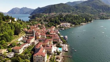 Havadan bakıldığında, parlak bir günde Como Gölü kıyısında kırmızı kiremitli çatıları olan bir kasaba görülüyor. Arka planda yemyeşil dağlar görülebilir..
