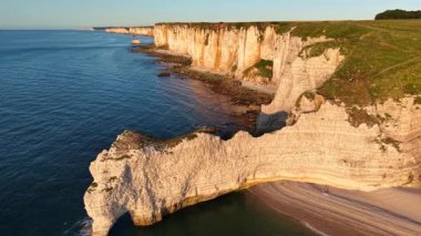 Altın saat boyunca Etretat Fransa 'nın muhteşem beyaz tebeşir kayalıklarının üzerinde süzülerek doğal kemerleri ve mavi okyanusu gözler önüne serdi..