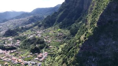Madeira Portekiz 'deki yemyeşil dağların arasına yerleşmiş büyüleyici bir kasabanın hava manzarasına tanık olun. Güneşli bir günde teraslı tarlalara ve evlere bakın.
