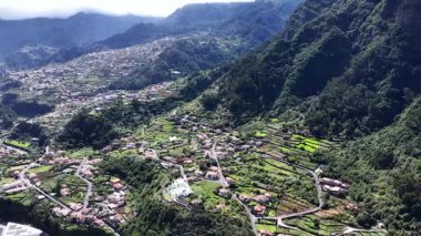 Yüksek açı, Madeira Portekiz 'in yeşil vadisindeki güzel bir köye bakıyor. Teraslı tarlalar ve virajlı yollar manzaraya ekleniyor..