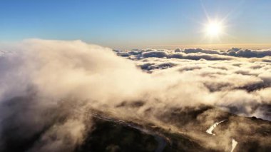Madeira Portekiz 'de güzel bir gündoğumunda bulutlar dağların tepelerinde yuvarlanır. Altın ışık gökyüzünü ve manzarayı aydınlatır..