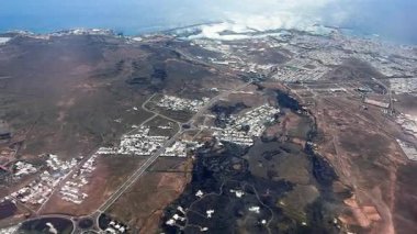Lanzarote adası üzerinde hava perspektifi. Sahil kasabaları yolları ve eşsiz volkanik arazi berrak mavi okyanusa doğru uzanıyor..