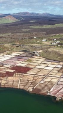 Lanzarote 'deki Janubio Salt Flats' ı yukarıdan araştır. Renkli tuz buharlaşması göletleri volkanik arazi ve okyanusla çelişiyor..