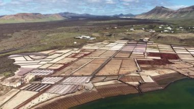 Hava görüntüsü Lanzarote 'deki Salinas de Janubio' nun tuzlu tavalarını gösteriyor. Açık bir günde parlak renkler havuzlara yansıyor.